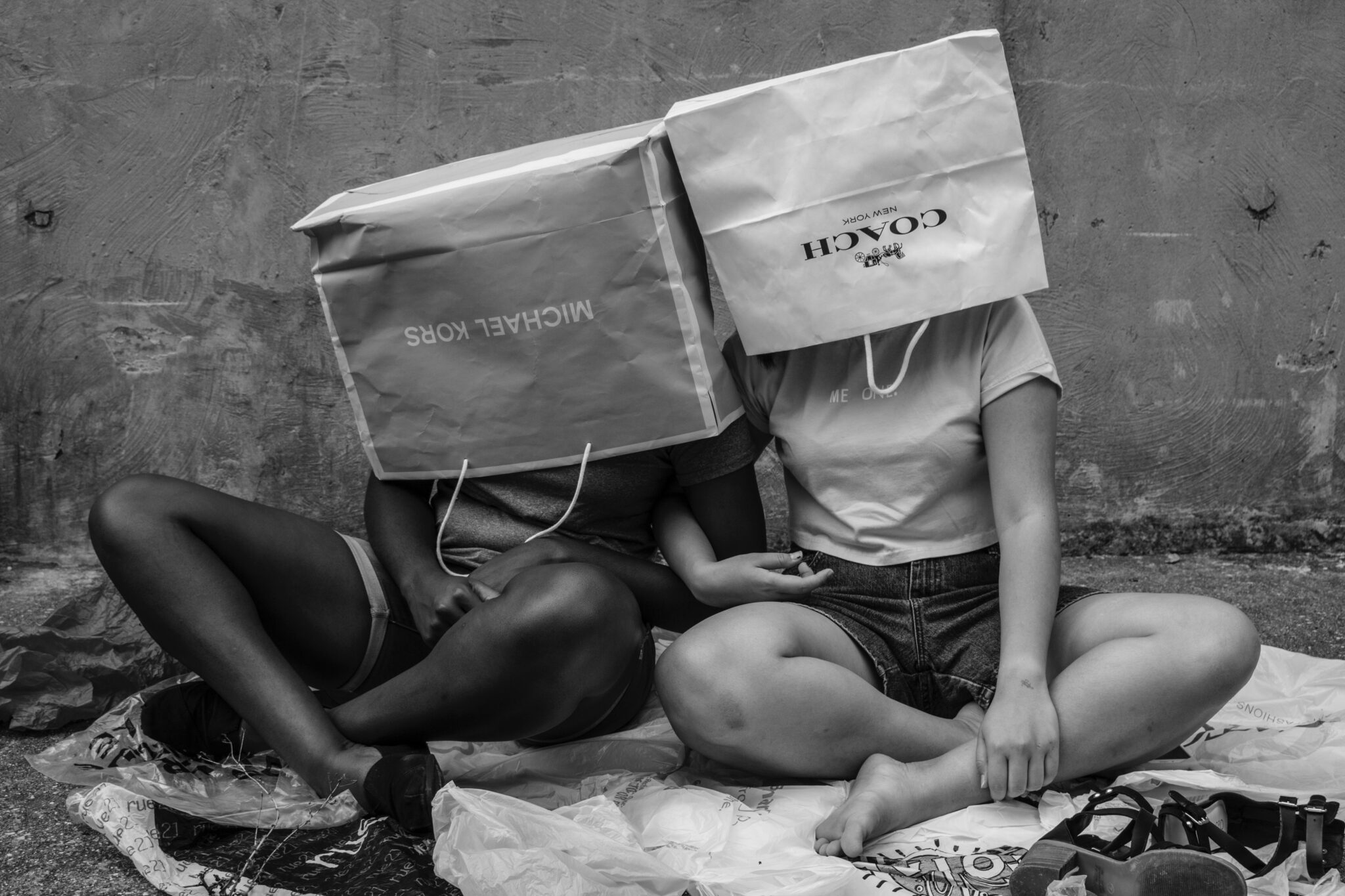 black and white girls with shopping bags on their heads symbolizing consumerism