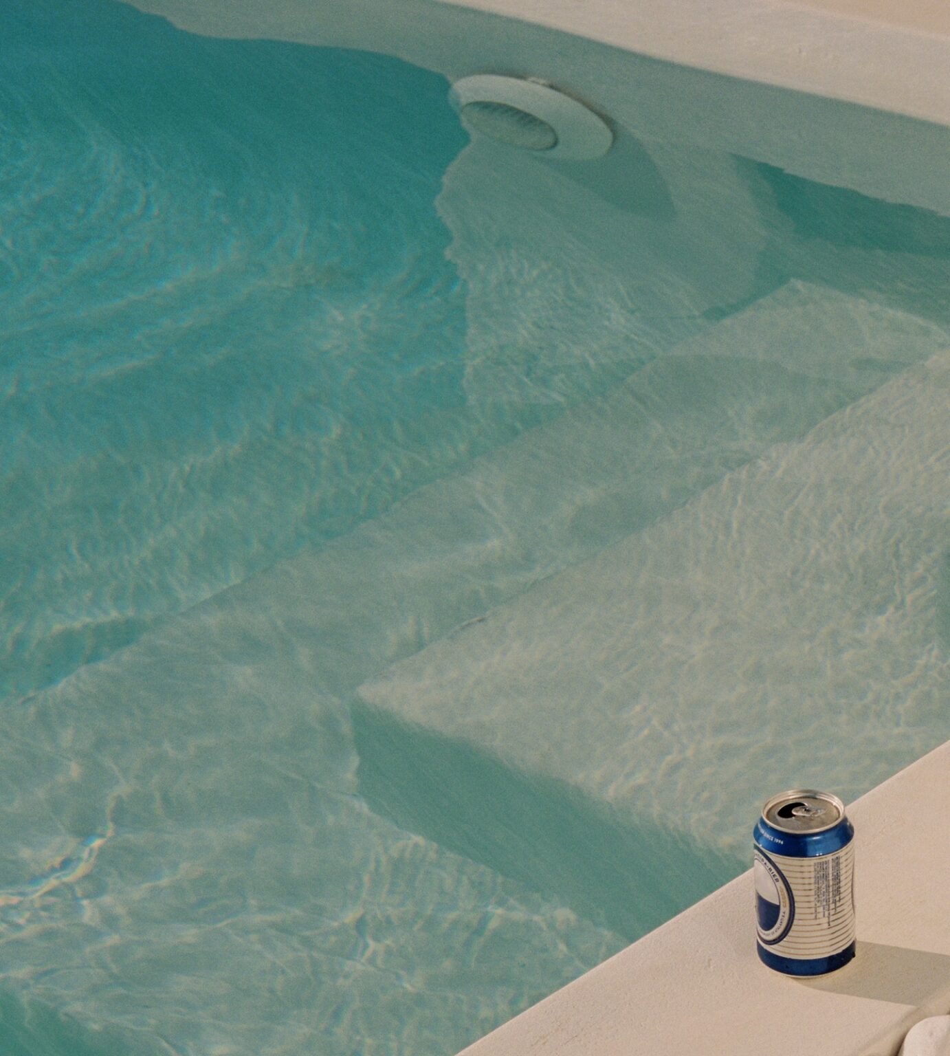 Can of soda sitting beside leisure pool